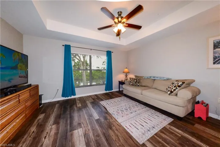 Bedroom with ceiling fan, a tray ceiling, and luxury vinyl wood-style flooring