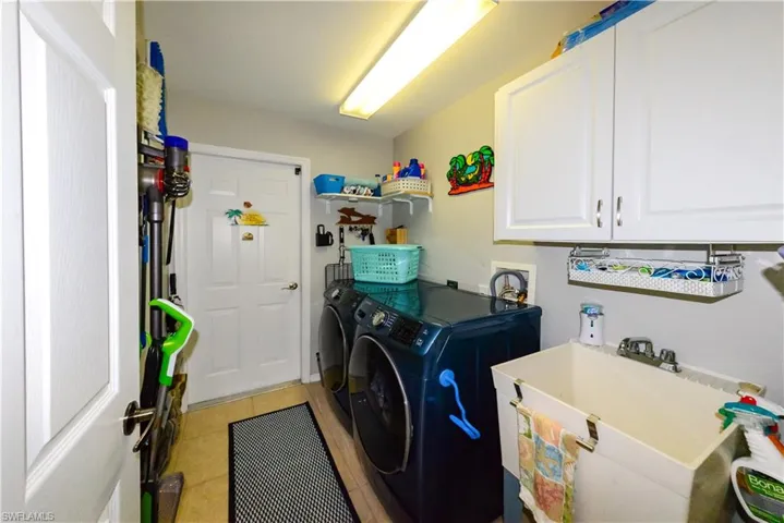 Clothes washing area featuring washer and dryer, cabinets, and sink.