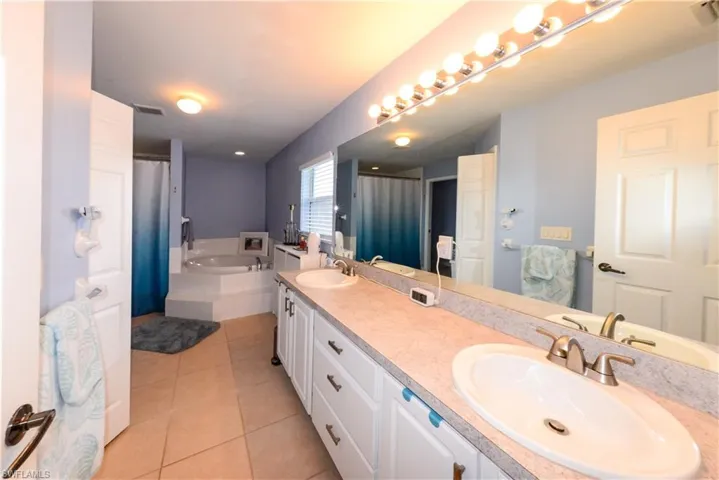 Bathroom with a bath, tile floors, and dual bowl vanity