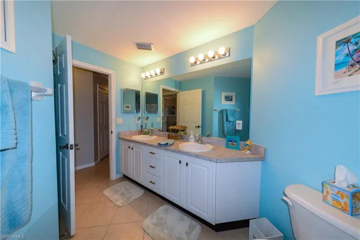Bathroom featuring double vanity, tile flooring, and toilet