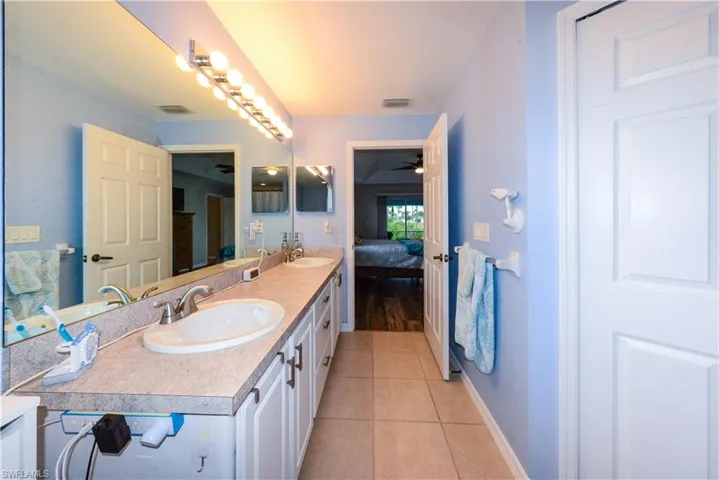 Bathroom with tile flooring, double sink, ceiling fan, and oversized vanity