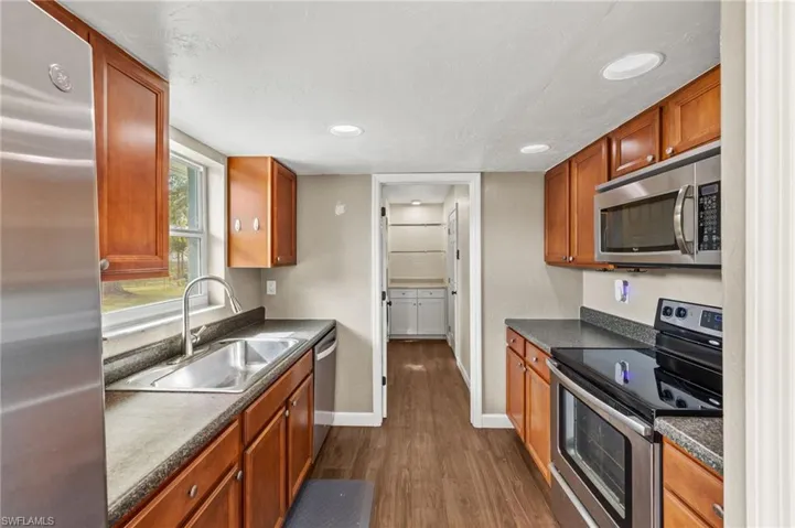 Kitchen with appliances with stainless steel finishes, dark hardwood / wood-style floors, and sink