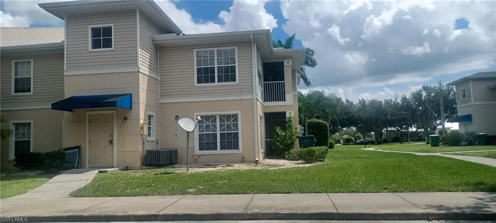 View of front of home with a balcony, a front lawn, and stucco siding