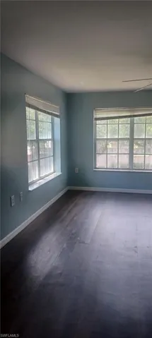Unfurnished room with healthy amount of natural light, dark wood finished floors, and ceiling fan