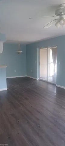 Unfurnished living room with dark wood-style flooring and a ceiling fan