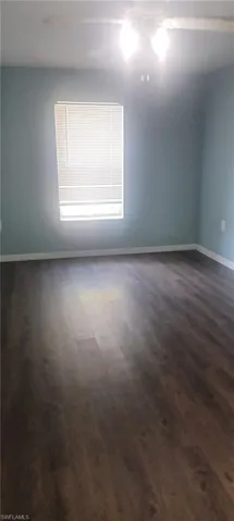 Spare room with dark wood-style floors and baseboards