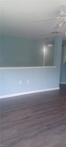 Unfurnished room with a ceiling fan and dark wood-type flooring