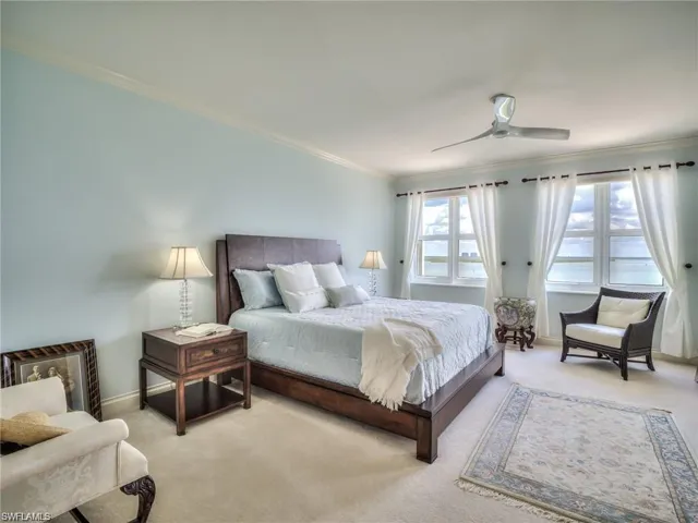 Carpeted bedroom with ceiling fan and crown molding