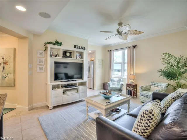 Living room with light tile patterned floors, ceiling fan, and crown molding