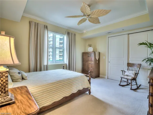 Carpeted bedroom with a closet, ornamental molding, and ceiling fan