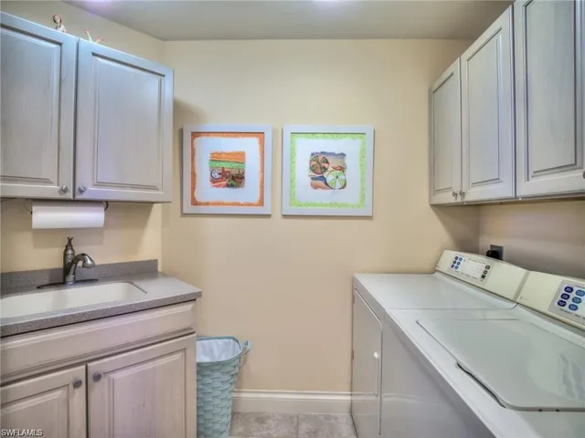 Laundry room with cabinets, separate washer and dryer, sink, and light tile patterned floors