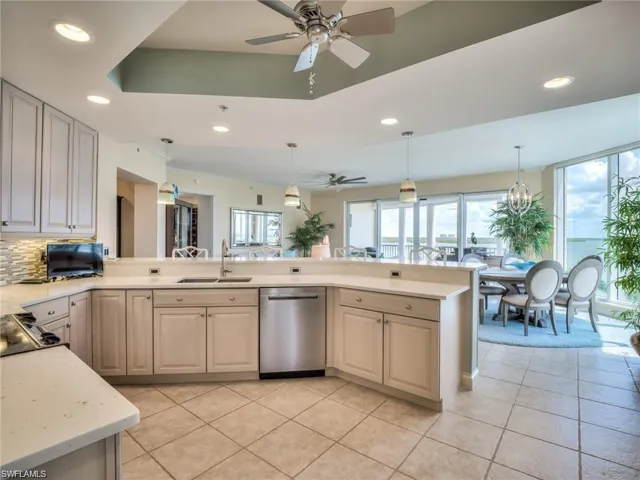 Kitchen featuring dishwasher, ceiling fan with notable chandelier, sink, hanging light fixtures, and kitchen peninsula
