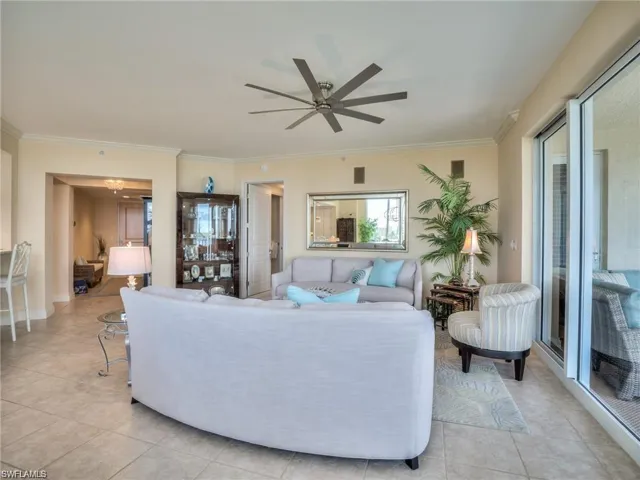 Tiled living room featuring crown molding and ceiling fan with notable chandelier