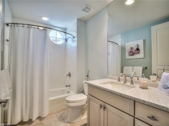 Full bathroom with toilet, vanity, tile patterned floors, and shower / bath combo with shower curtain