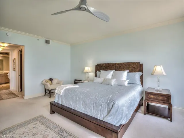 Carpeted bedroom with ensuite bath, ceiling fan, ornamental molding, and sink