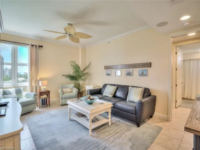 Living room with ceiling fan, ornamental molding, and light tile patterned flooring
