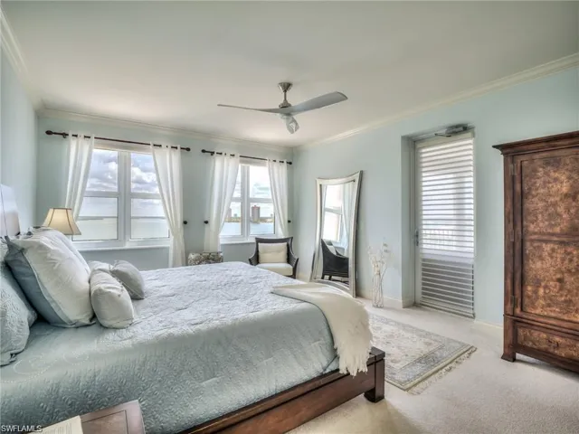 Carpeted bedroom featuring ceiling fan and crown molding