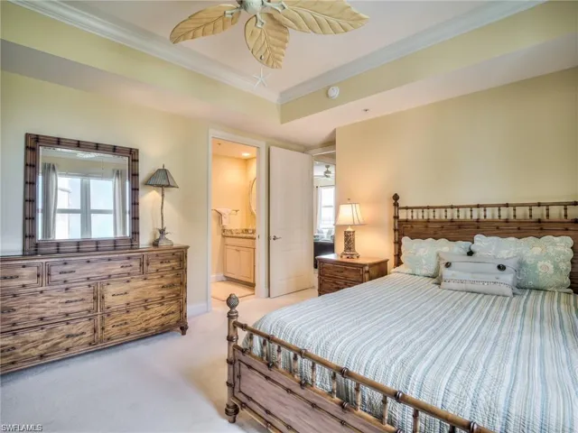 Carpeted bedroom with ensuite bathroom, ceiling fan, and ornamental molding