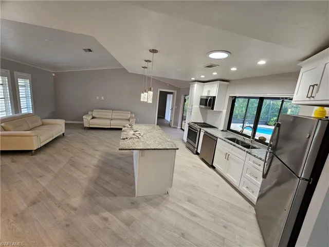Kitchen featuring appliances with stainless steel finishes, open floor plan, visible vents, and a sink