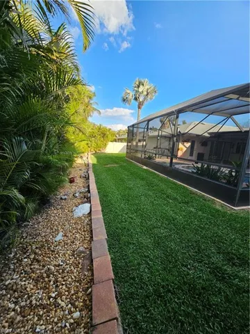 View of yard with fence and a lanai
