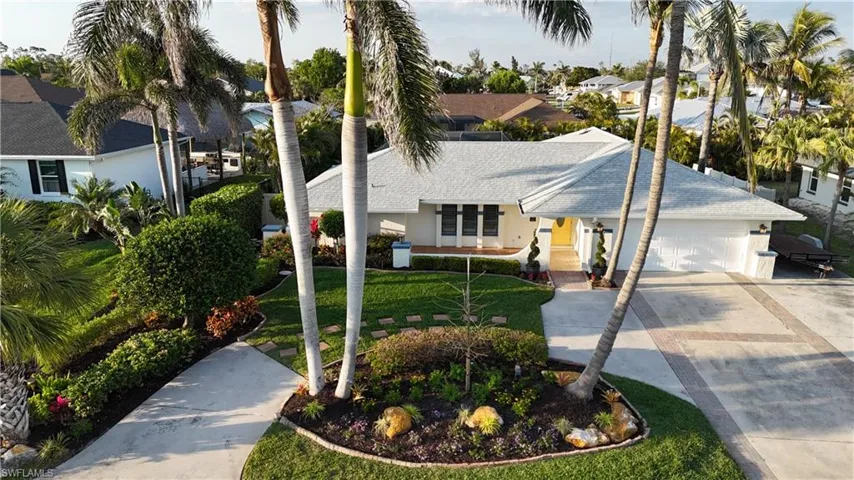 View of front facade featuring a shingled roof, concrete driveway, an attached garage, a front lawn, and stucco siding