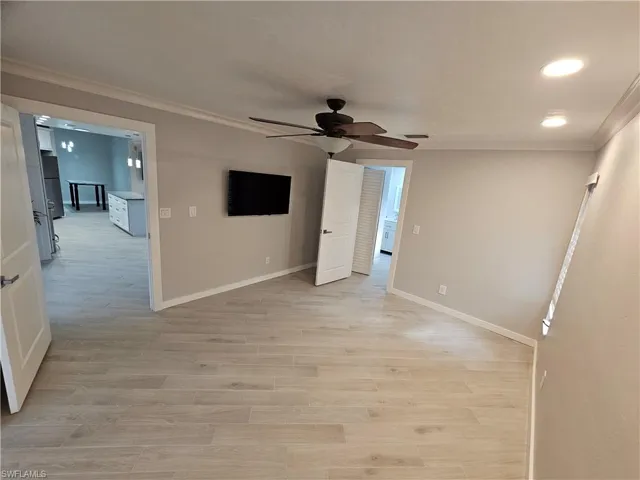 Unfurnished room with light wood-style flooring, a ceiling fan, baseboards, visible vents, and crown molding
