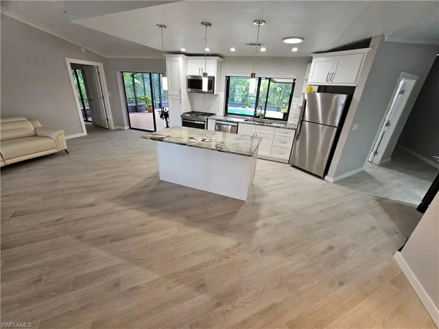 Kitchen featuring white cabinets, a center island, stainless steel appliances, a healthy amount of sunlight, and a sink