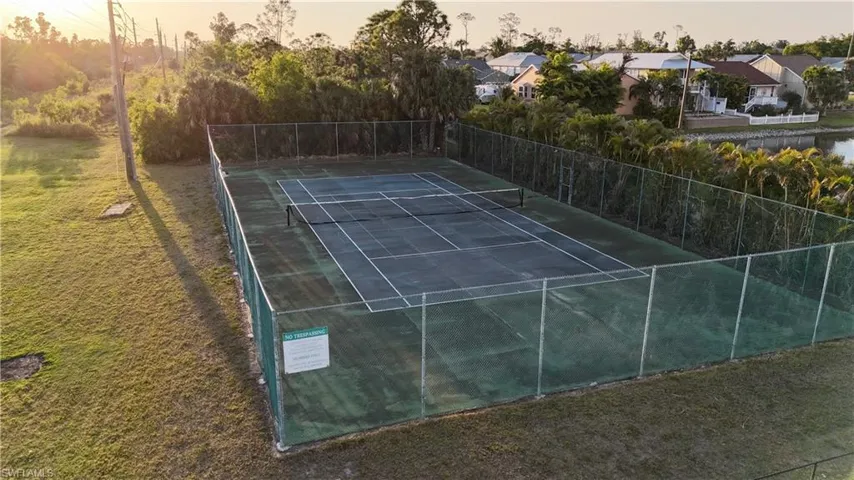 View of tennis court featuring a residential view and fence