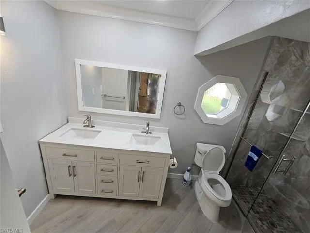 Bathroom featuring crown molding, a stall shower, a sink, and toilet