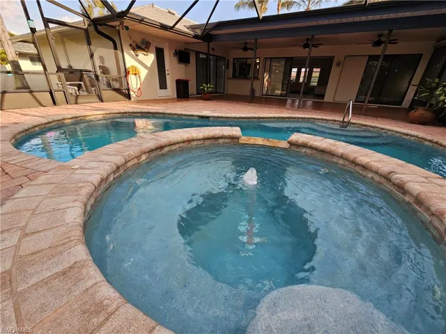View of pool with a ceiling fan, a pool with connected hot tub, a patio area, and a lanai
