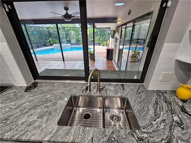 Interior details featuring stone countertops, a pool, a sink, and ceiling fan