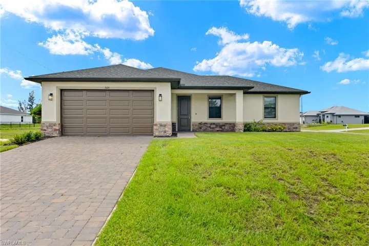 View of front of property featuring a garage and a front lawn