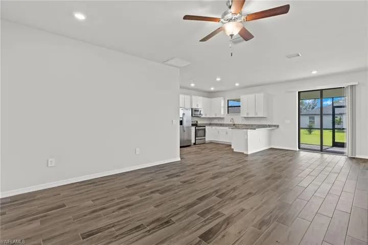 Unfurnished living room featuring dark wood-type flooring and ceiling fan