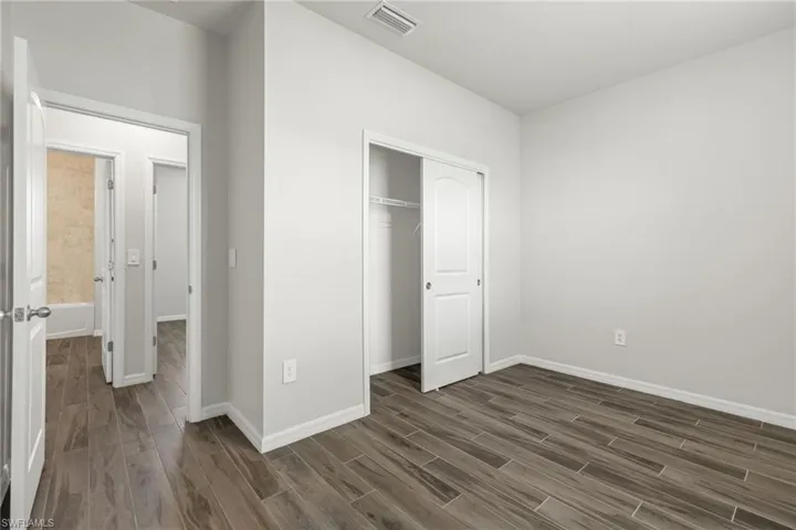 Unfurnished bedroom featuring dark hardwood / wood-style flooring and a closet