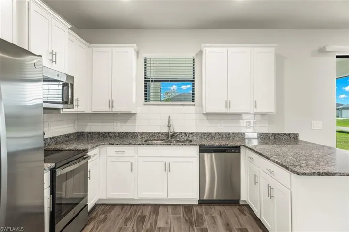 Kitchen with sink, decorative backsplash, appliances with stainless steel finishes, and wood-type flooring