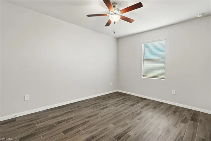 Empty room with dark hardwood / wood-style flooring and ceiling fan