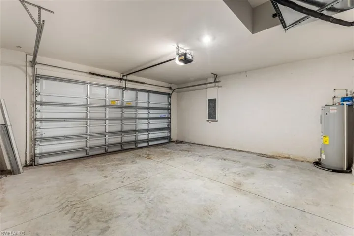 Garage featuring electric water heater and a garage door opener