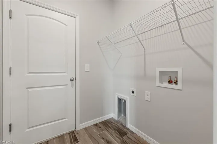 Clothes washing area with hookup for a washing machine, hardwood / wood-style flooring, and hookup for an electric dryer