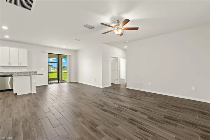 Unfurnished living room featuring dark wood-type flooring and ceiling fan