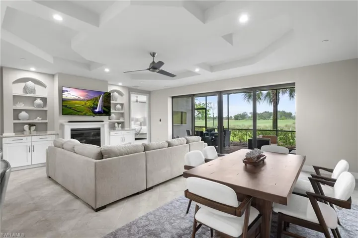 Living room with built in shelves, a ceiling fan, a glass covered fireplace, and recessed lighting