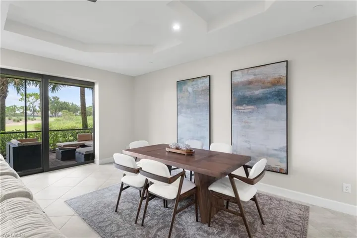 Dining space with light tile patterned floors, a tray ceiling, and recessed lighting