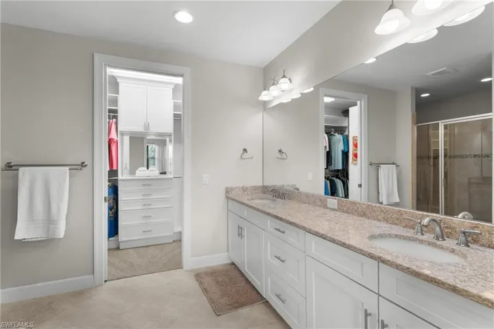 Full bathroom with double vanity, a walk in closet, a stall shower, and recessed lighting