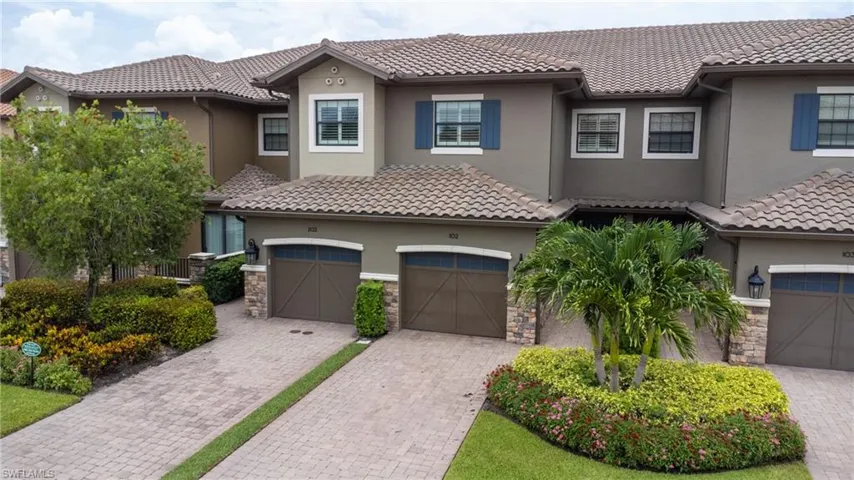 View of front of house featuring stucco siding, a tile roof, and driveway