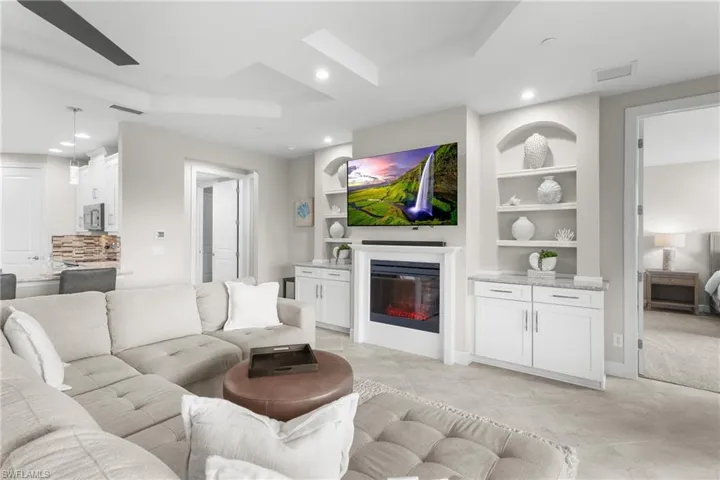 Living room featuring built in shelves, recessed lighting, and a glass covered fireplace