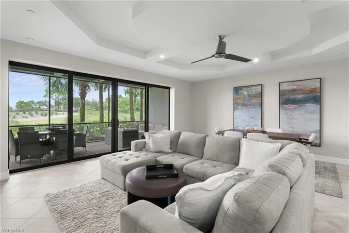 Living area with a ceiling fan, light tile patterned flooring, coffered ceiling, a raised ceiling, and recessed lighting