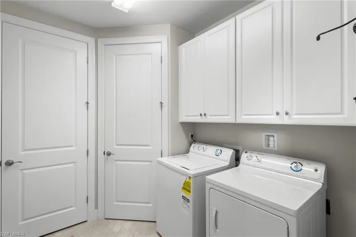 Laundry area with cabinet space, separate washer and dryer, and light tile patterned flooring