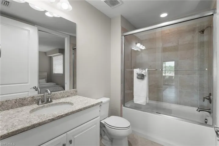 Full bathroom with vanity, ensuite bathroom, shower / bath combination with glass door, and recessed lighting