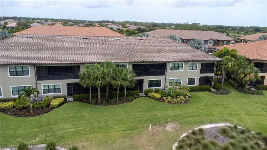 Rear view of house with a residential view, a tile roof, a lawn, and stucco siding