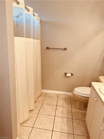 Full bath featuring a shower with shower curtain, vanity, and light tile patterned floors