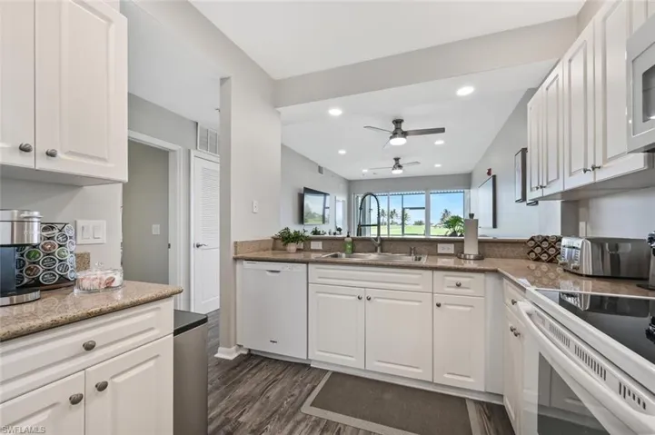 Kitchen with white appliances, sink, dark hardwood / wood-style flooring, kitchen peninsula, and white cabinetry